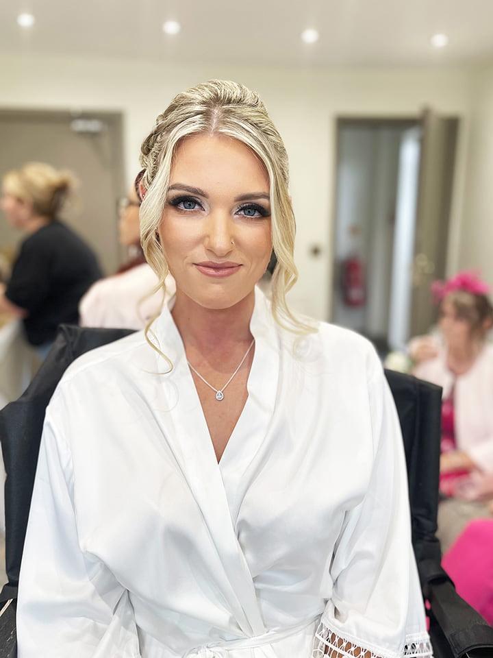 Bride in wedding dressing gown with makeup on